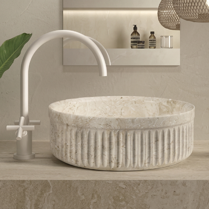 Lavabo redondo en mármol beige sobre encimera con relieve acanalado