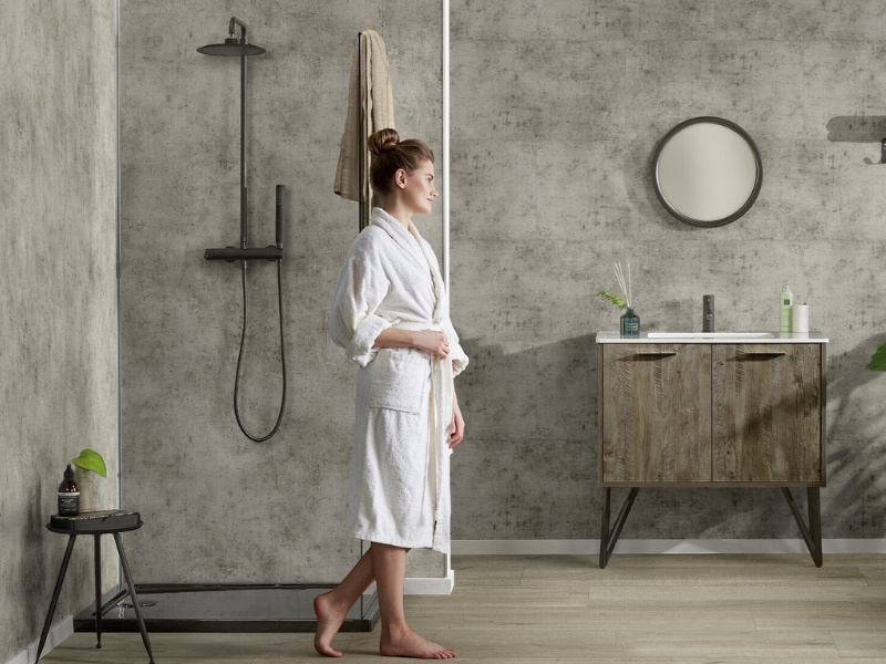 Baño moderno estilo industrial con ducha negra, mueble de madera y revestimiento efecto cemento